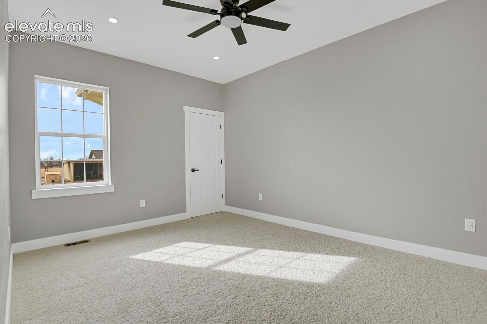 Recessed lighting, ceiling fan, grid window, paneled door, and light-colored carpeting