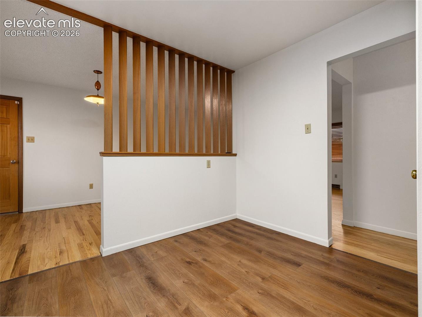 Wood-finish flooring throughout, a decorative wood slat partition, and a light wood door