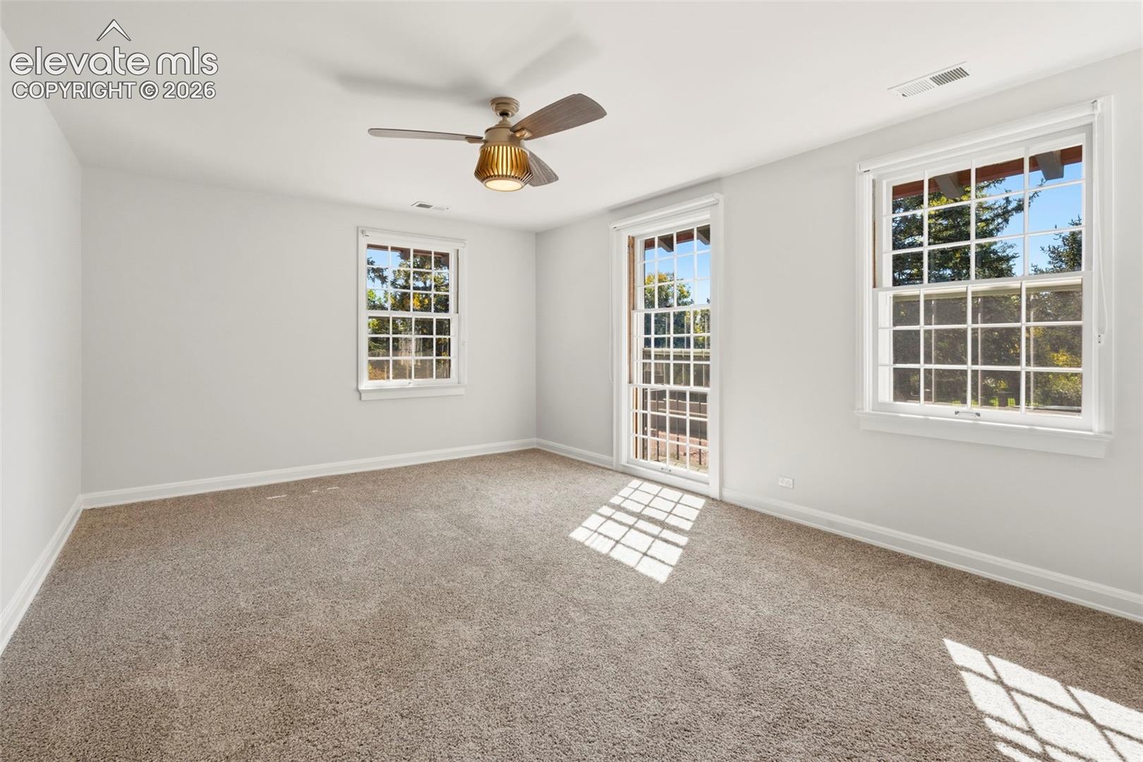 Neutral-toned wall finish, wall-to-wall carpeting, multi-pane windows, and a ceiling-mounted fan with integrated light fixture