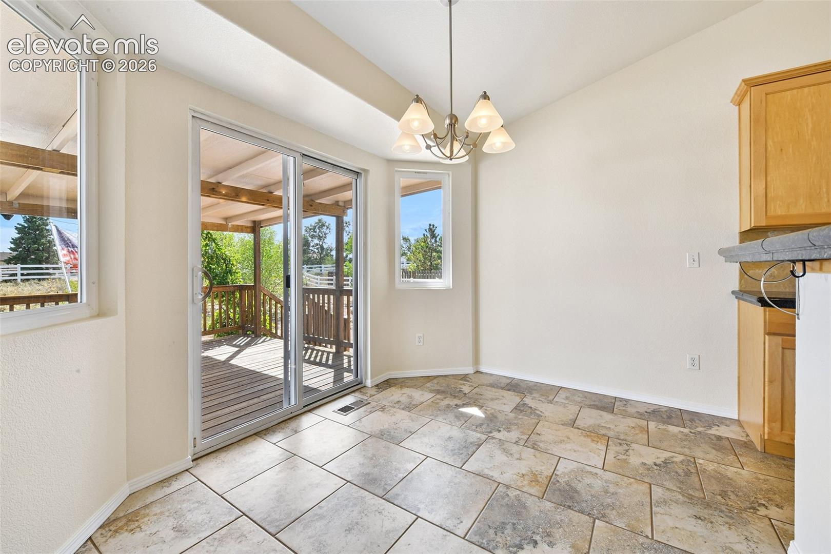 Tiled flooring and a ceiling-mounted light fixture illuminate this bright space, featuring a sliding glass door and multiple windows