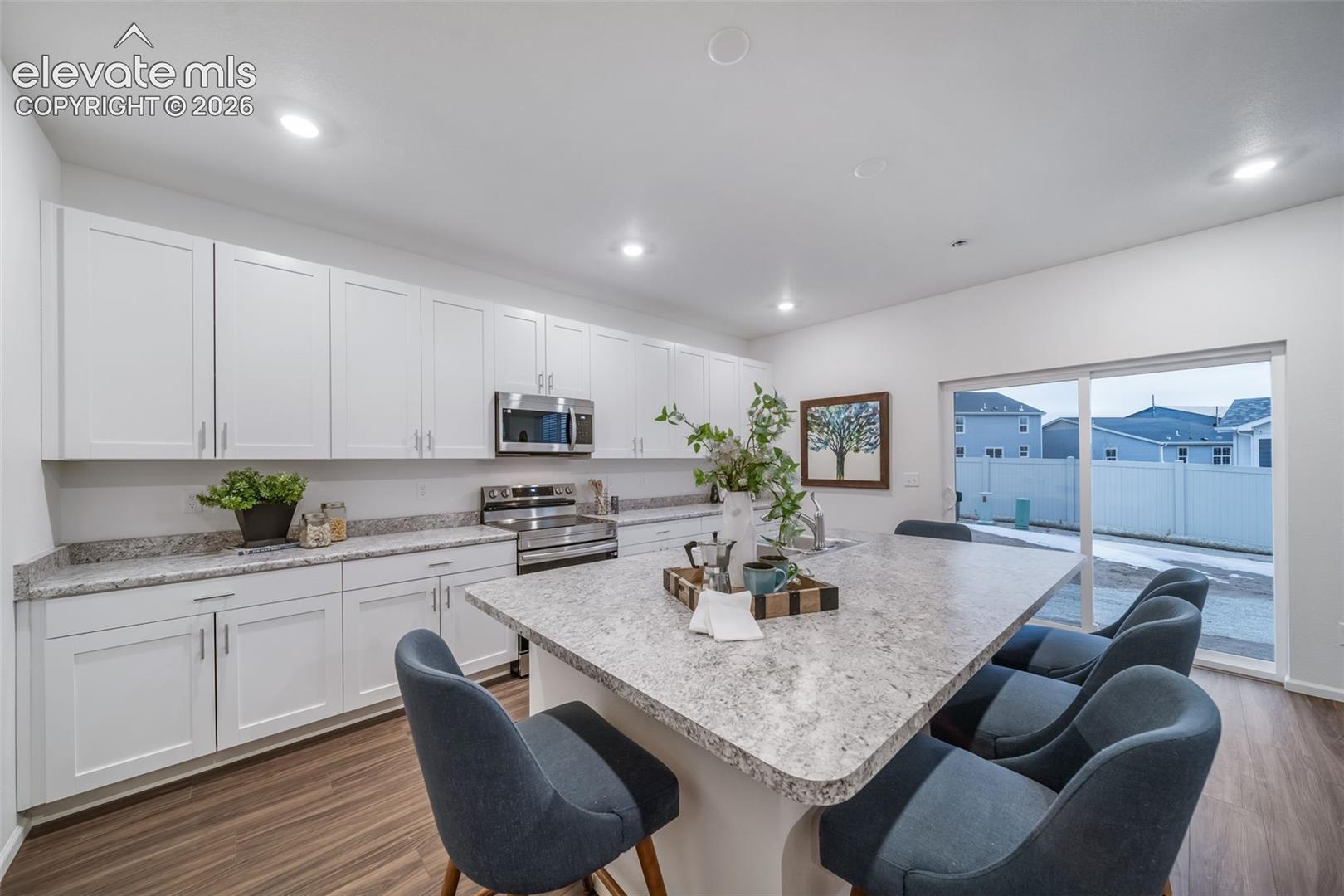 White cabinetry, light-toned countertops, stainless steel appliances, wood-finish flooring, and a sliding glass door
*photos of a model home*