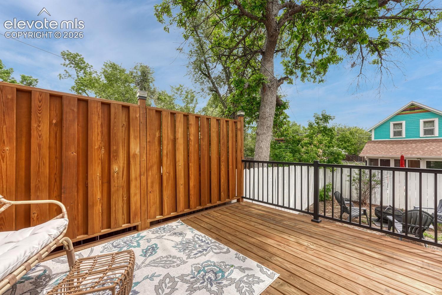 Spacious wood-decked patio featuring a privacy fence and black metal railings