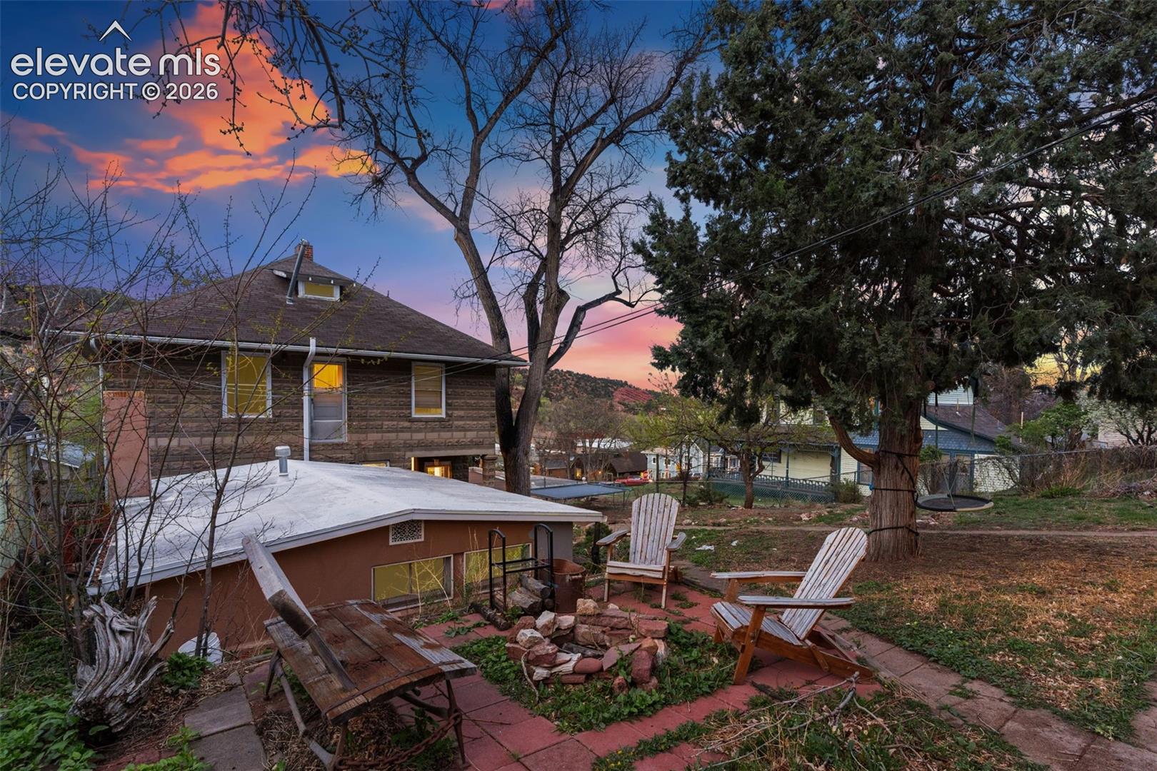 Back of main home and studio cottage with an outdoor fire pit and a sitting area