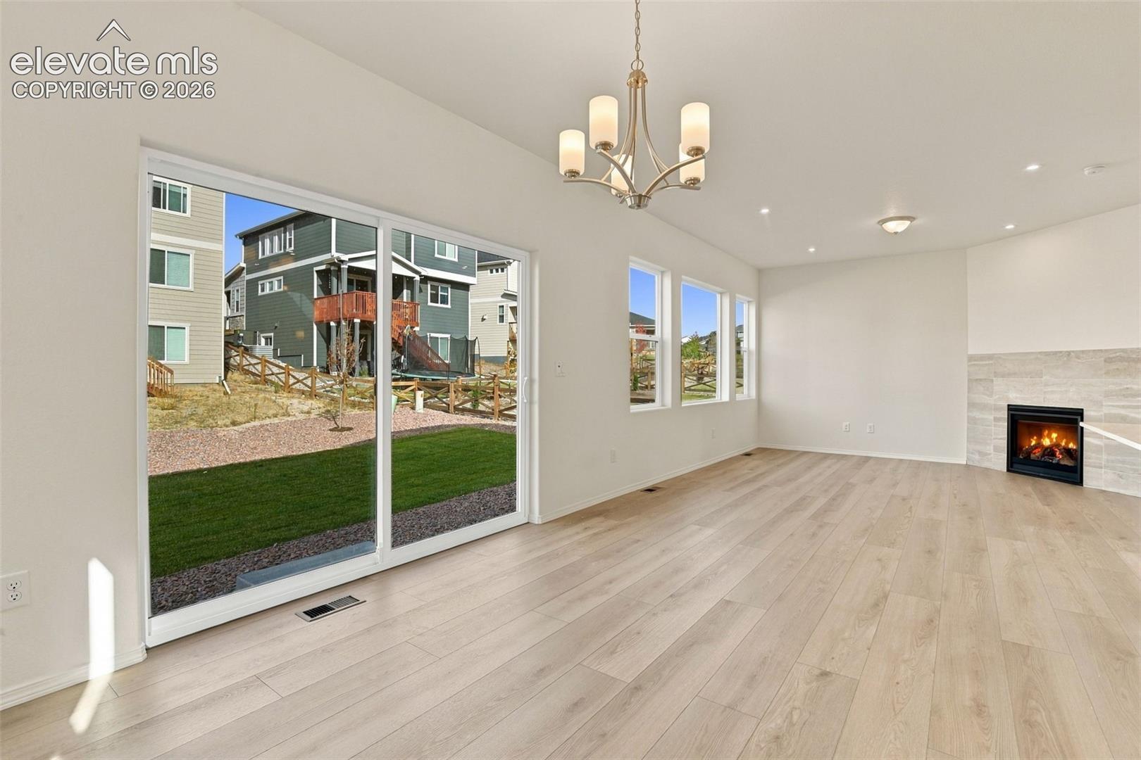 Living area featuring light wood-finish flooring, sliding glass patio doors, recessed lighting, a chandelier, and a fireplace with tile surround