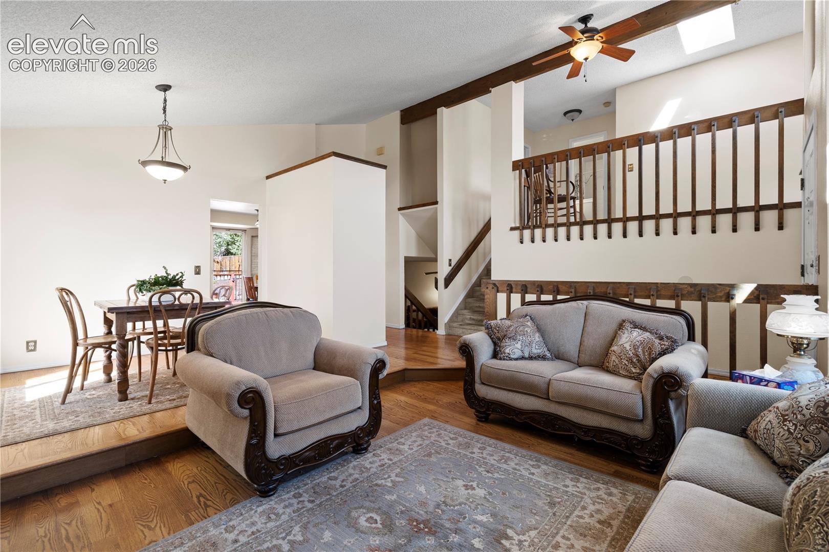 Hardwood flooring throughout, exposed wood beams, skylight, and a ceiling fan