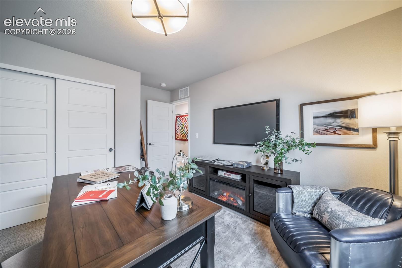 Versatile room featuring a large wood-finish desk, built-in shelving, sliding panel doors, and a ceiling-mounted light fixture
*Photos of a model home*