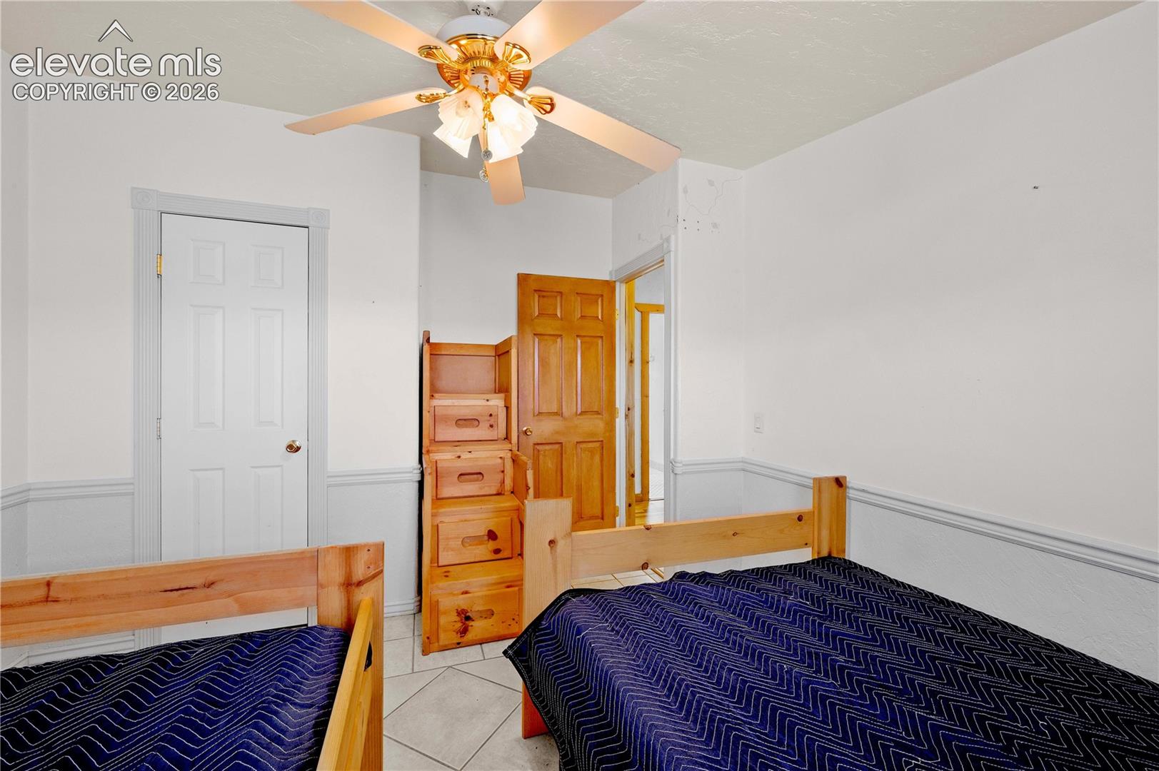 Tiled bedroom featuring ceiling fan