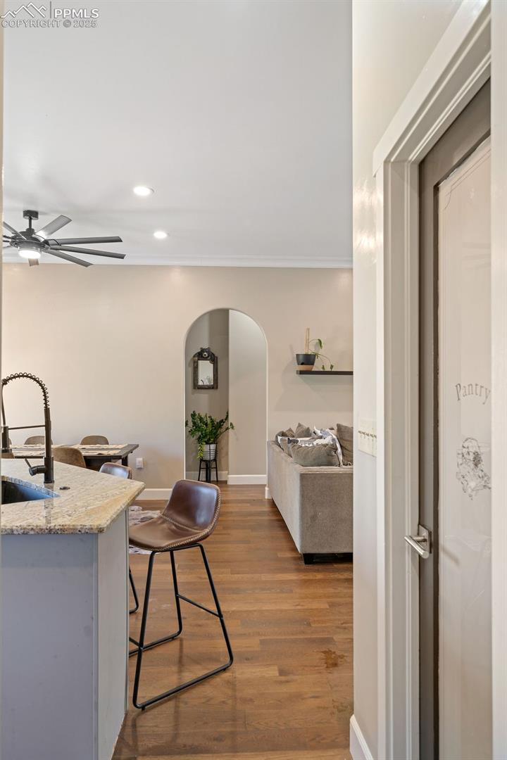 Kitchen featuring arched walkways, dark wood finished floors, recessed lighting, light stone countertops, and ceiling fan