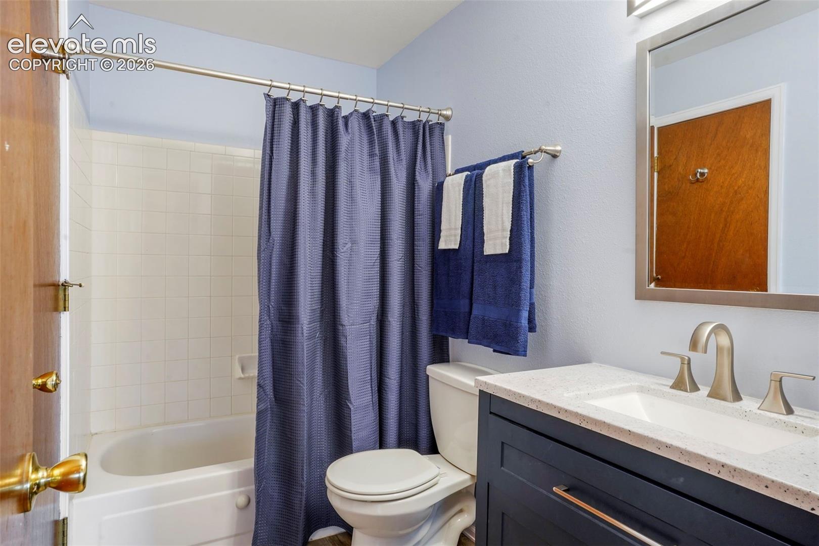 Full bathroom with shower / bath combination with curtain, vanity, and toilet