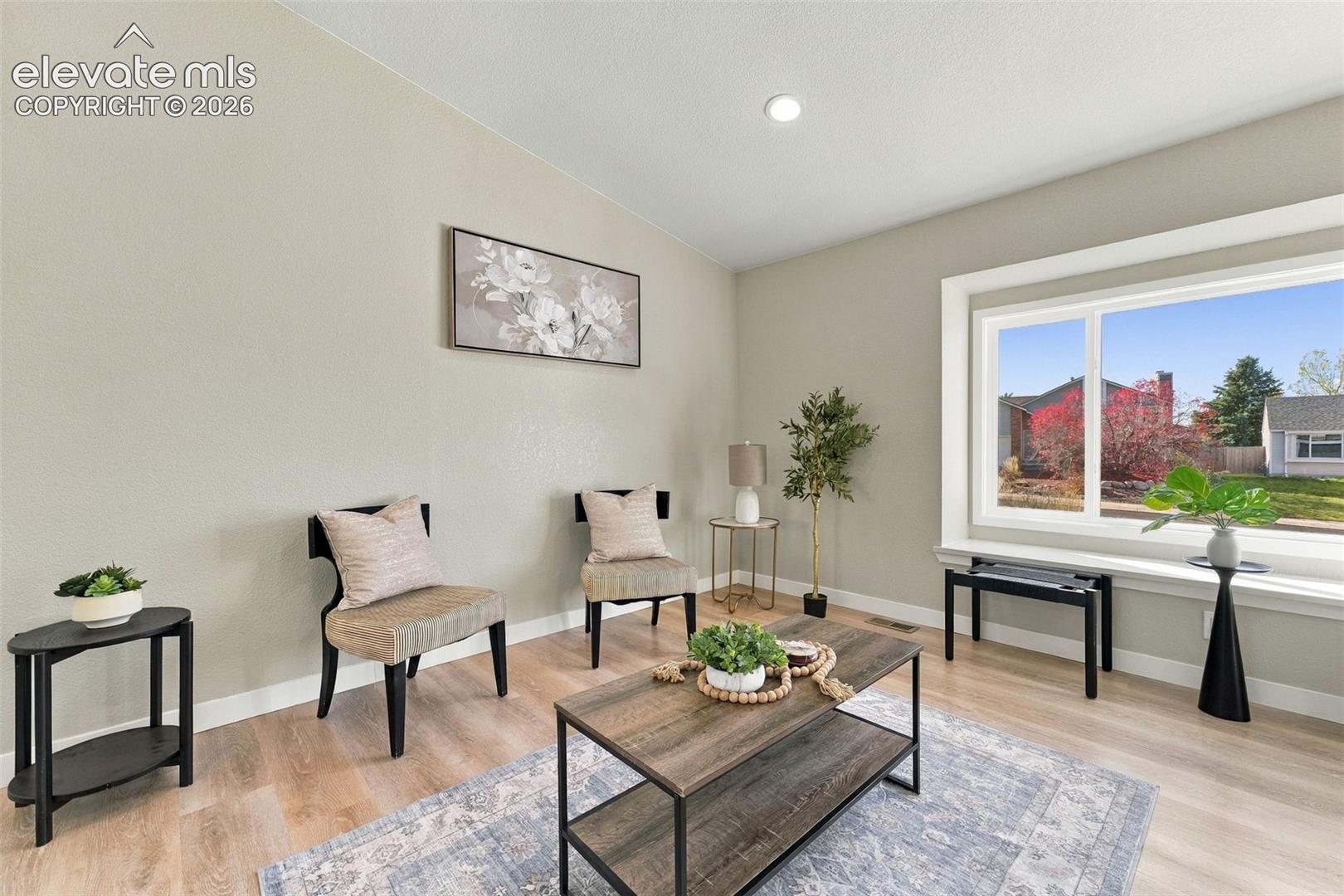 Vaulted ceiling, wood-finish flooring, and a large picture window with a deep sill