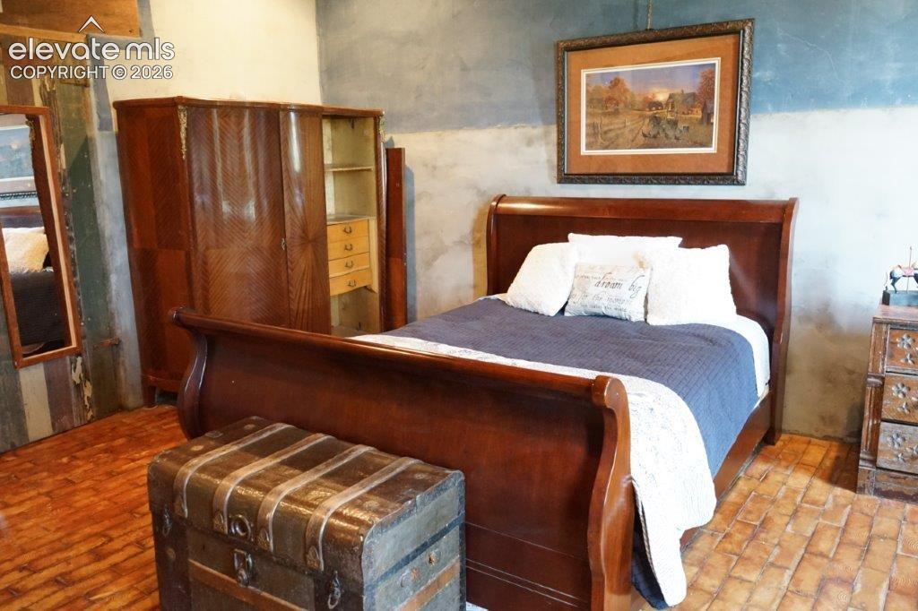 Bedroom featuring brick-patterned flooring, a slate-toned accent wall, and a built-in wardrobe with internal shelving