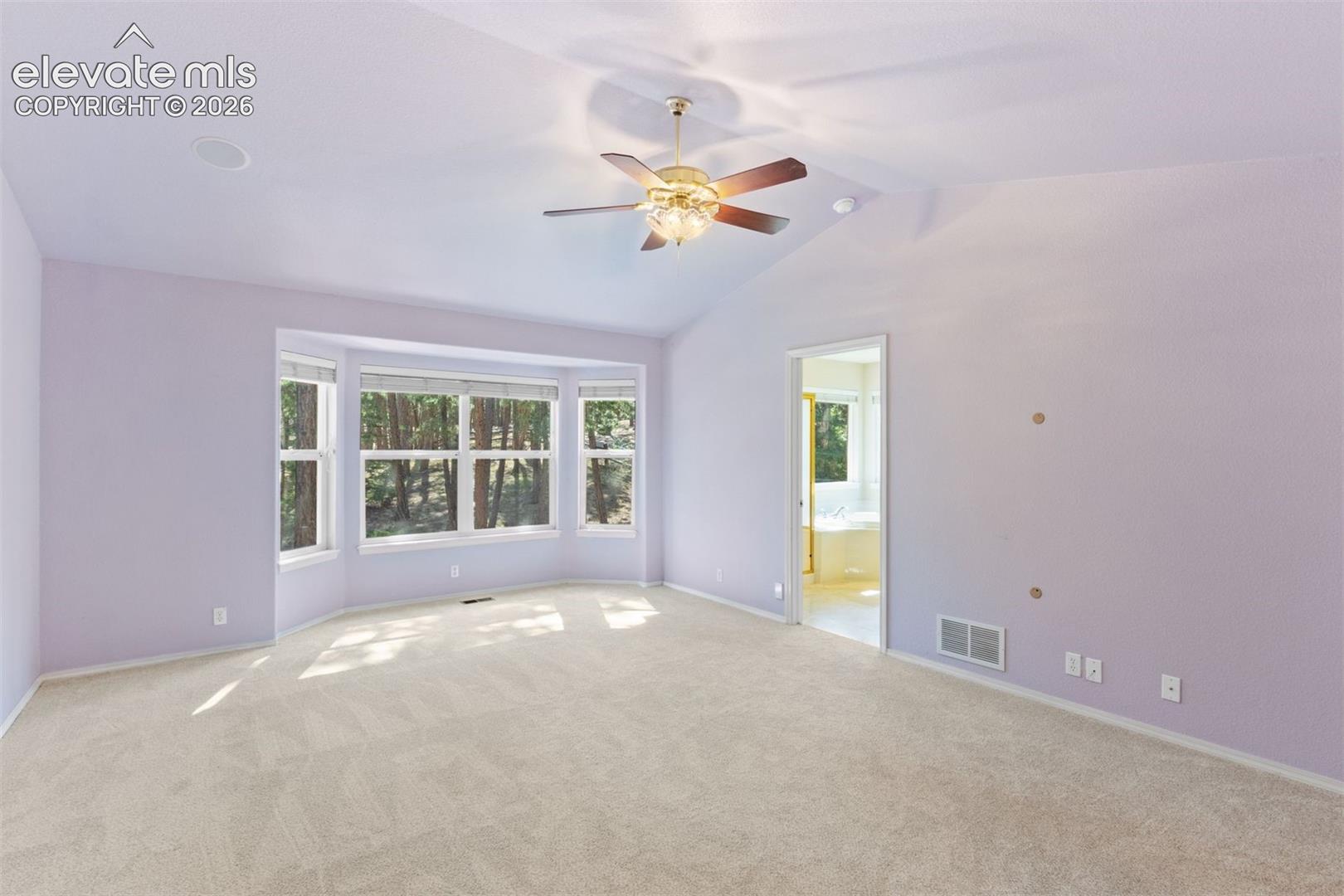 Primary bedroom with vaulted ceiling, french doors, ceiling fan, and ensuite bath