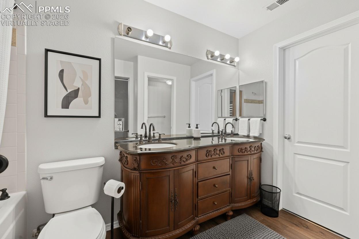 Full bath with double vanity, shower / bathtub combination with curtain, and wood finished floors. This photo is virtually staged.