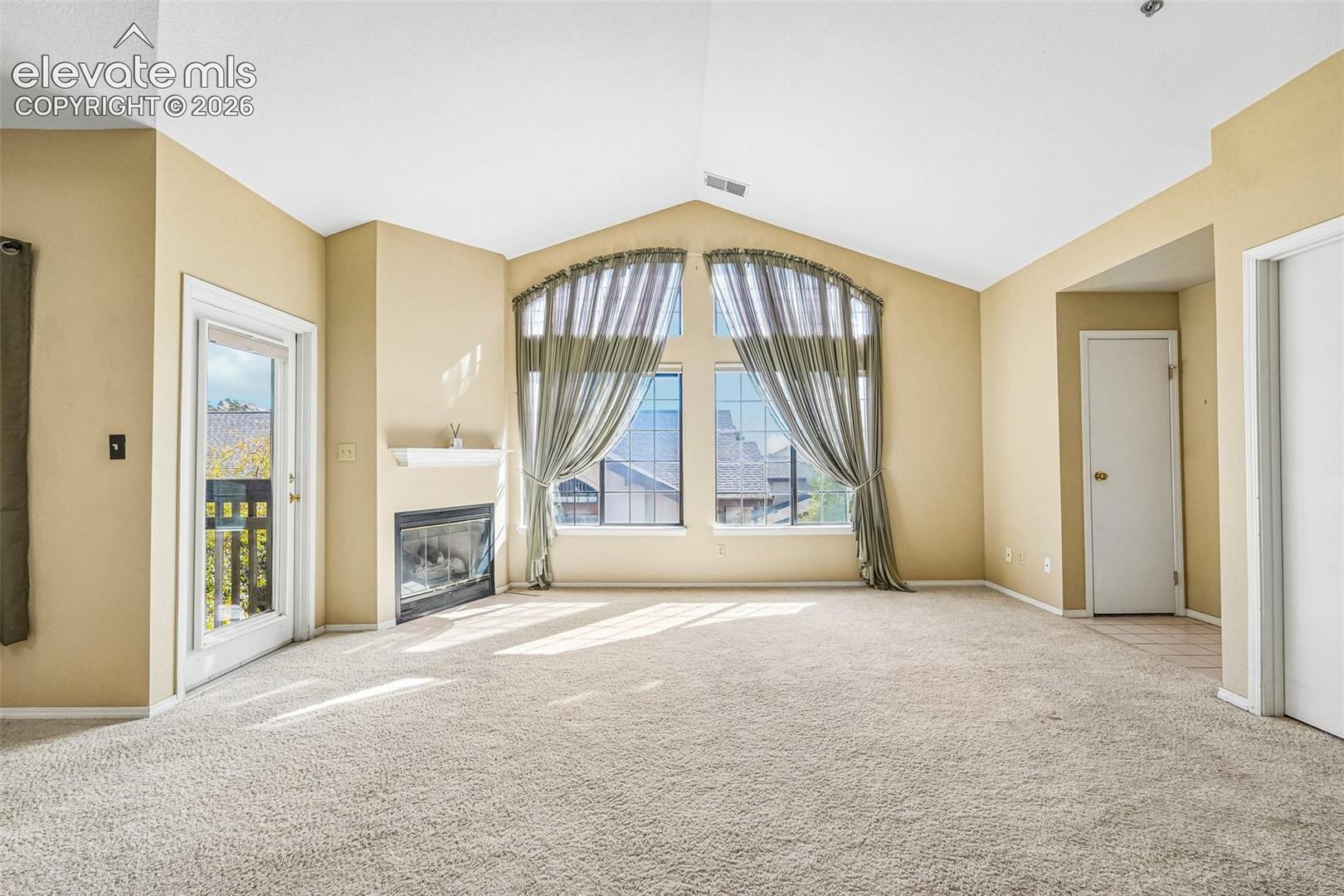 Living room with vaulted ceilings, a gas fireplace, a walk out and large windows brining in tons of natural light