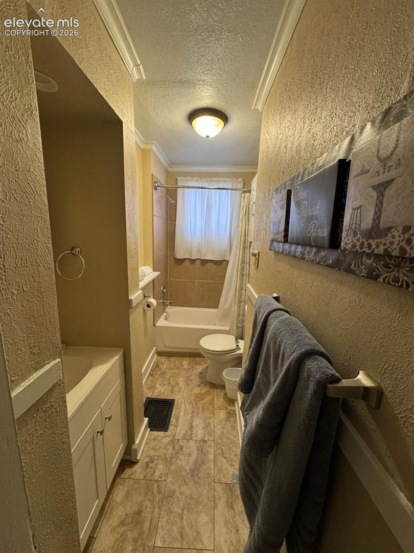 Full bathroom featuring a single vanity, crown molding, a built-in tub with a shower, and tile flooring