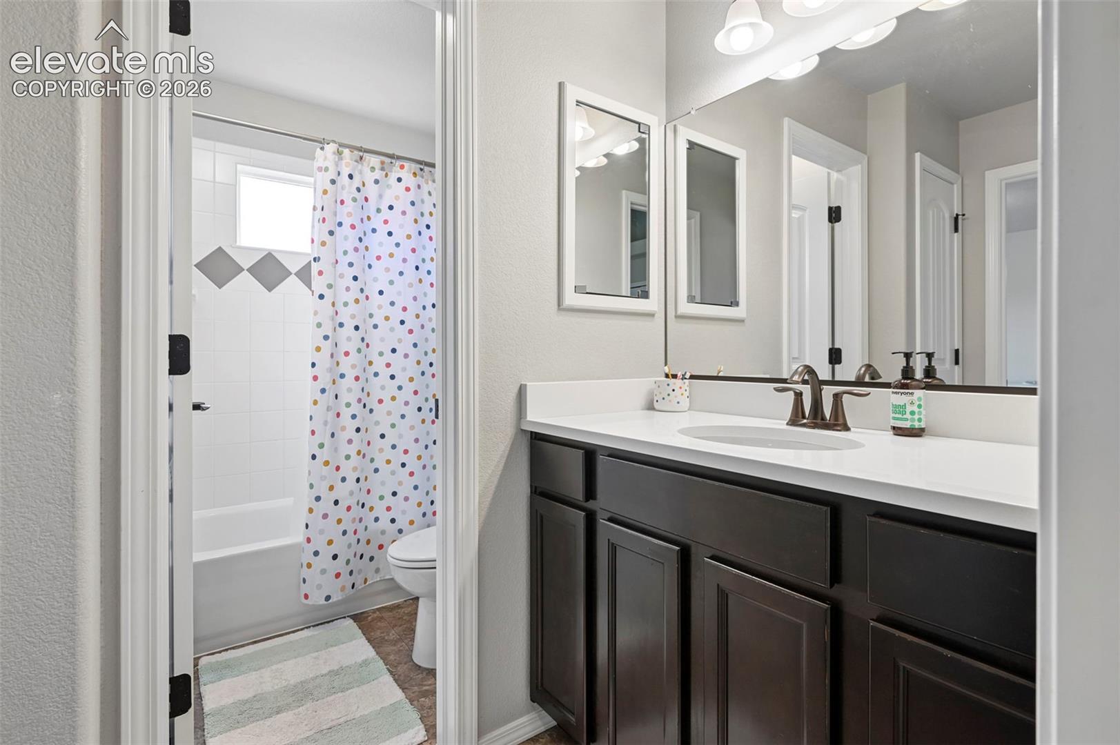 Bathroom vanity featuring dark wood-finish cabinetry and quartz countertop