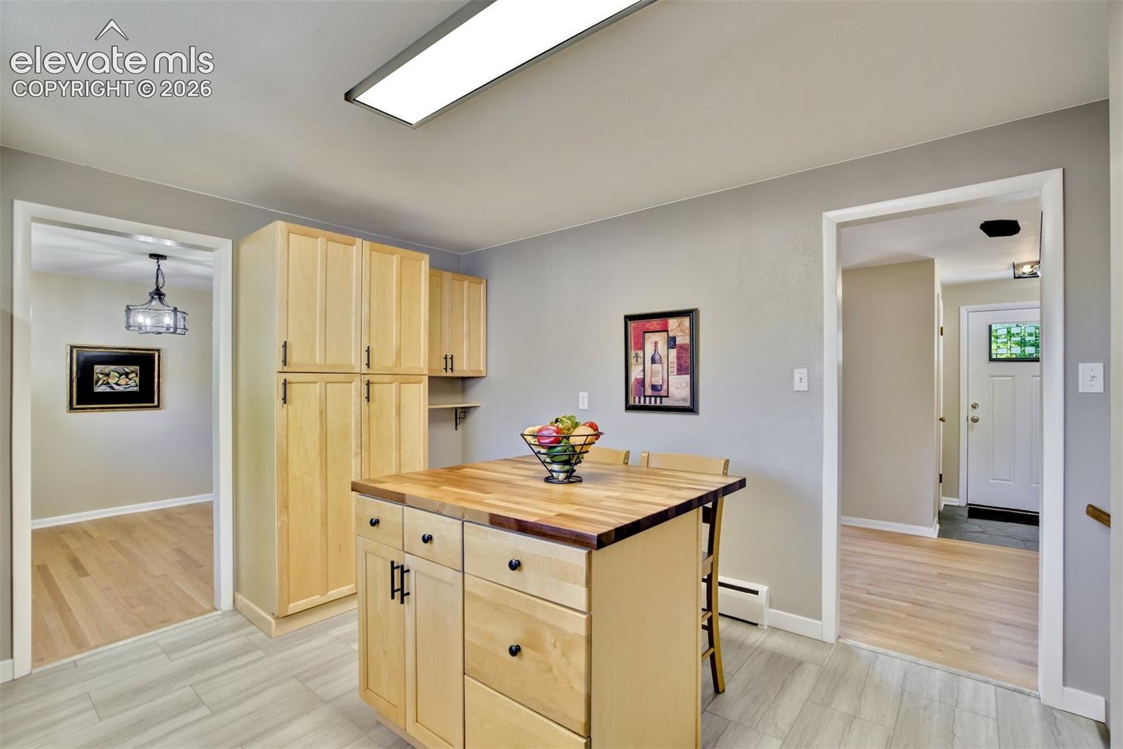 Custom light-toned wood cabinetry, center island with a wood-block surface, integrated storage drawers, and tile flooring
