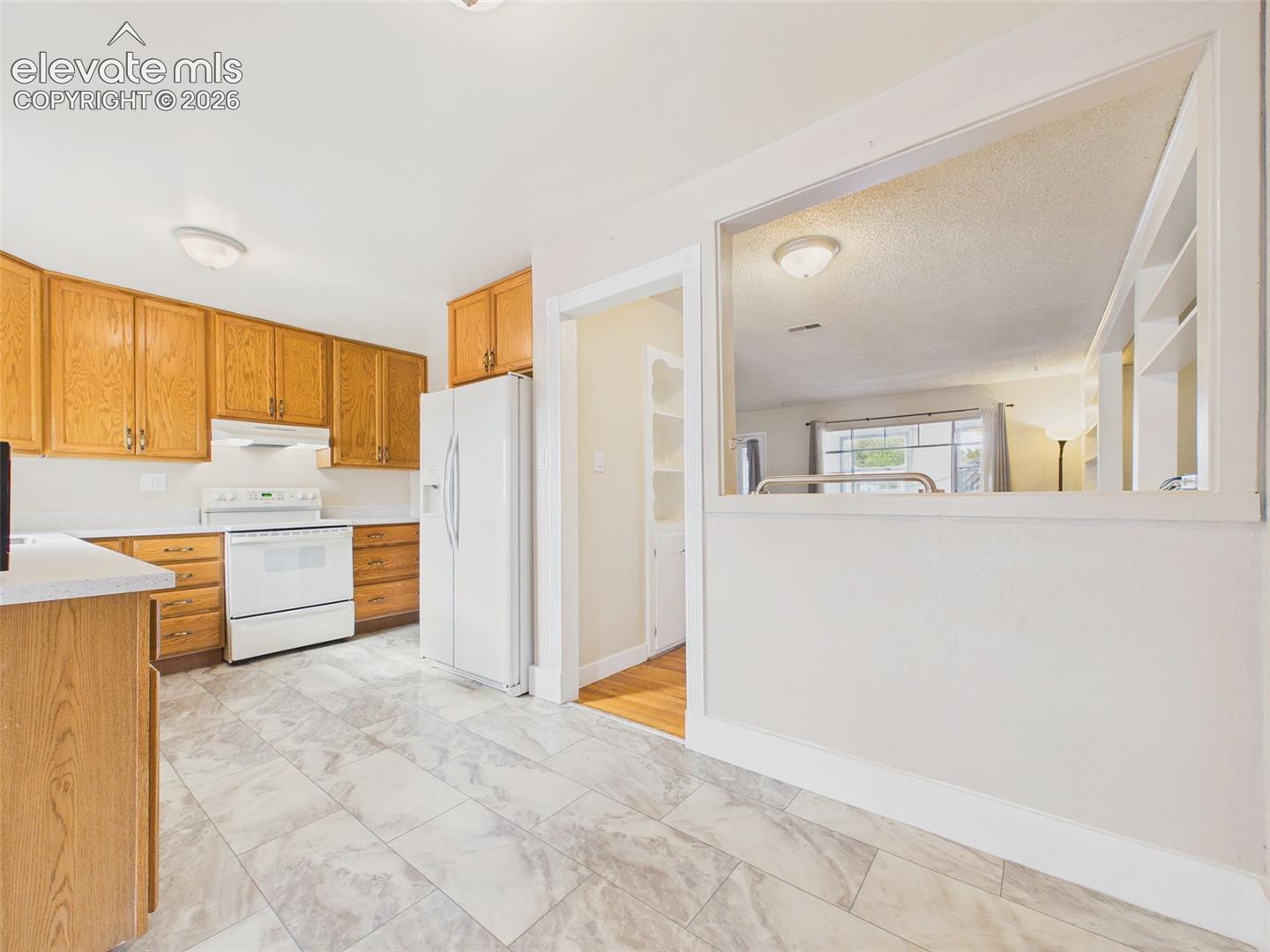 Another perspective of the kitchen showcasing the cabinetry, spacious countertops, and convenient access to the adjoining family room with a freestanding wood stove.