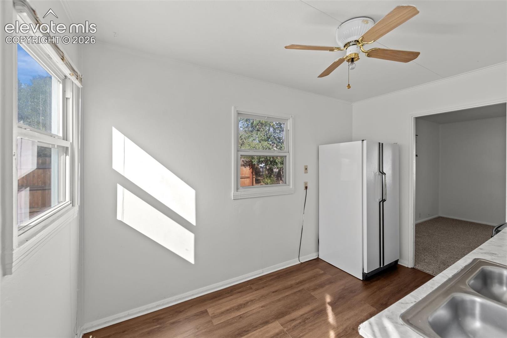 Kitchen featuring wood-finish flooring, dual-pane windows, a stainless steel double-basin sink, and a ceiling fan