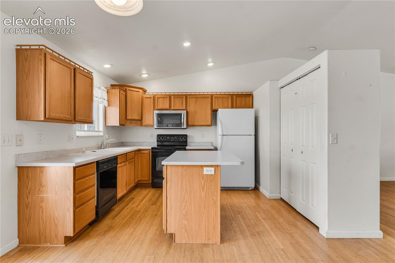 Kitchen featuring wood-finish cabinetry, light-colored countertops, wood-finish flooring, and recessed lighting