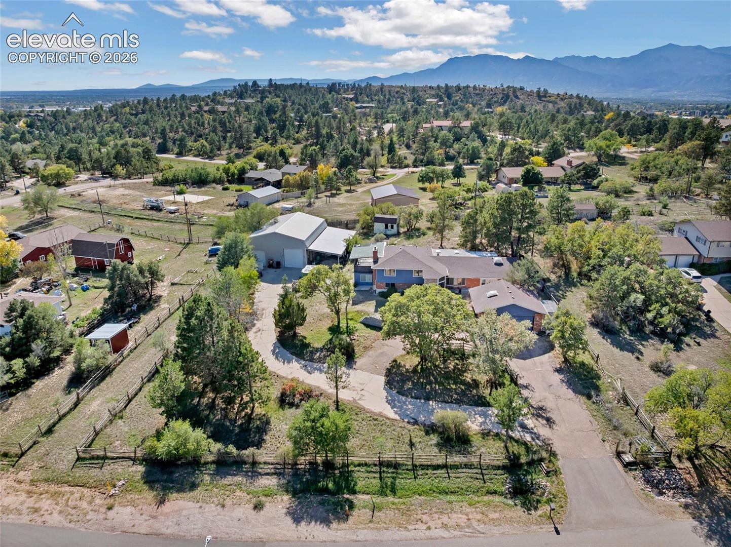 Expansive property featuring a paved driveway, mature trees, and mountainous scenery
