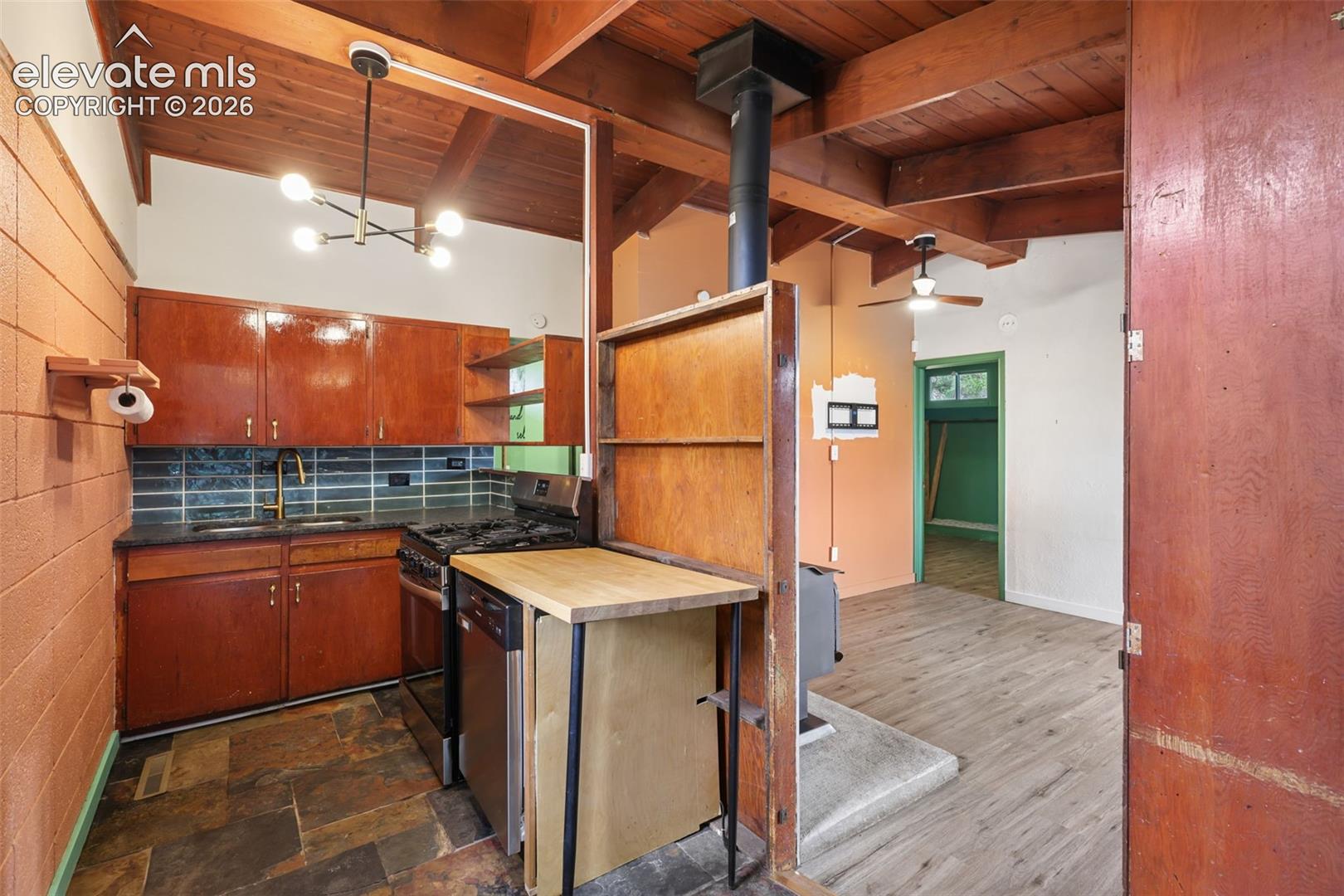 Kitchen featuring wood cabinetry, stone-look tile flooring, and a subway tile backsplash