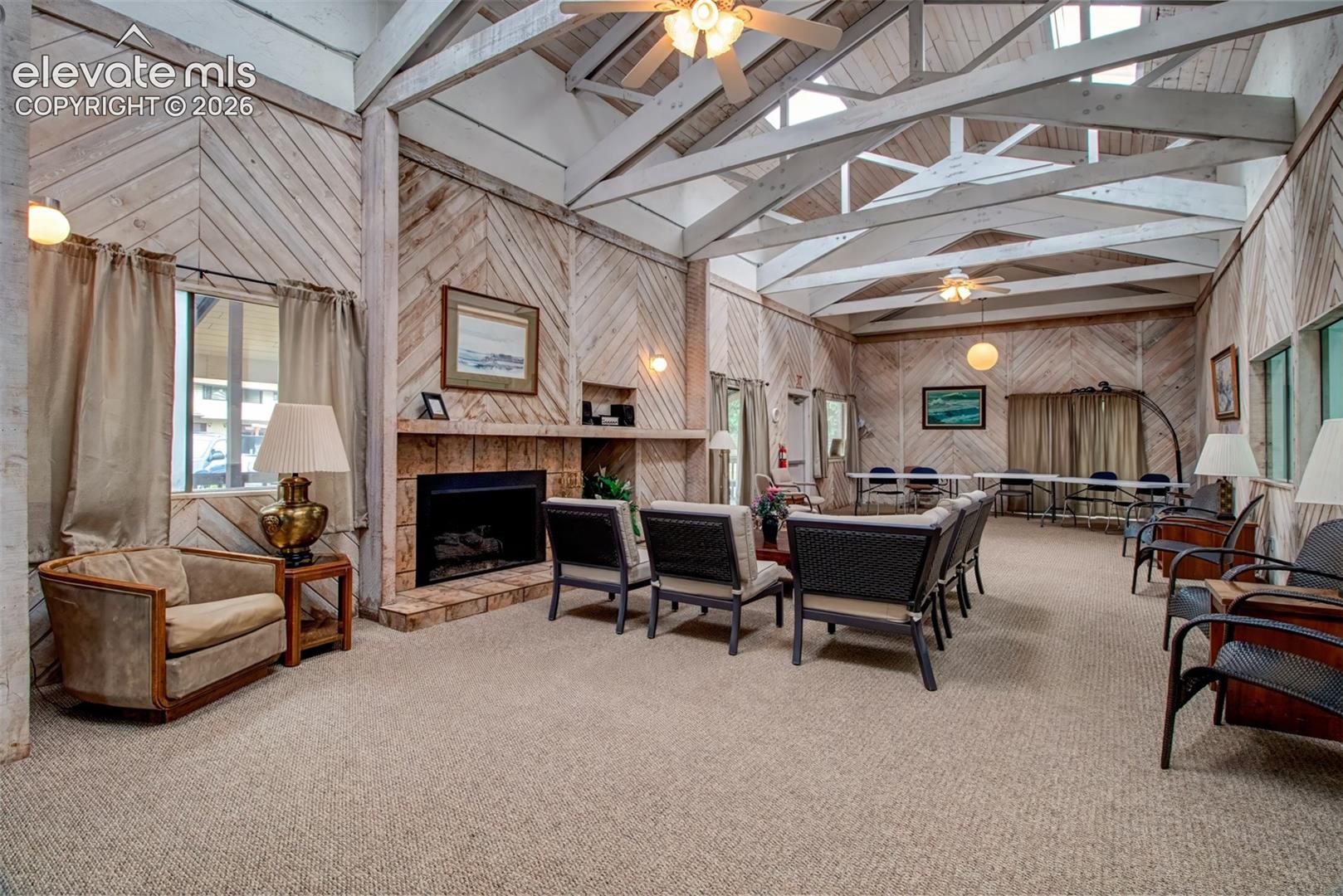 Vaulted ceilings with exposed timber trusses, diagonal wood-paneled walls, and a floor-to-ceiling stone-surround fireplace