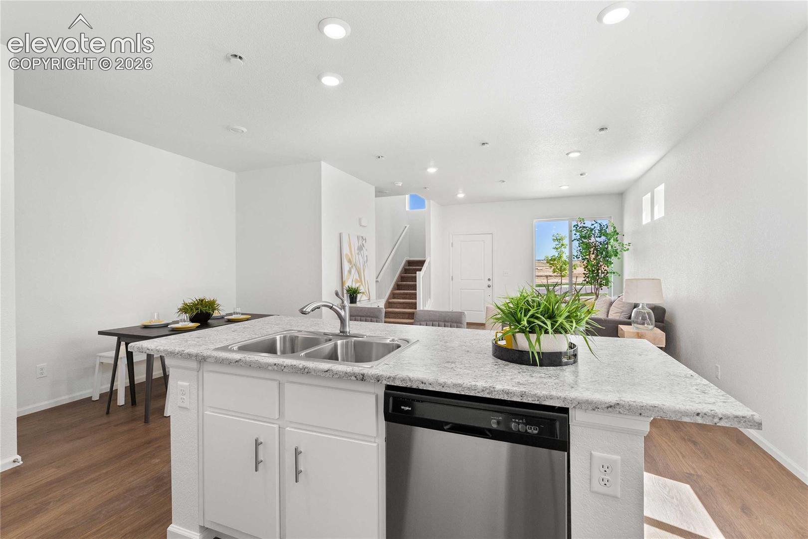 Kitchen island with dual stainless steel sink, integrated dishwasher, and light-toned countertop
*photos  of a model home*