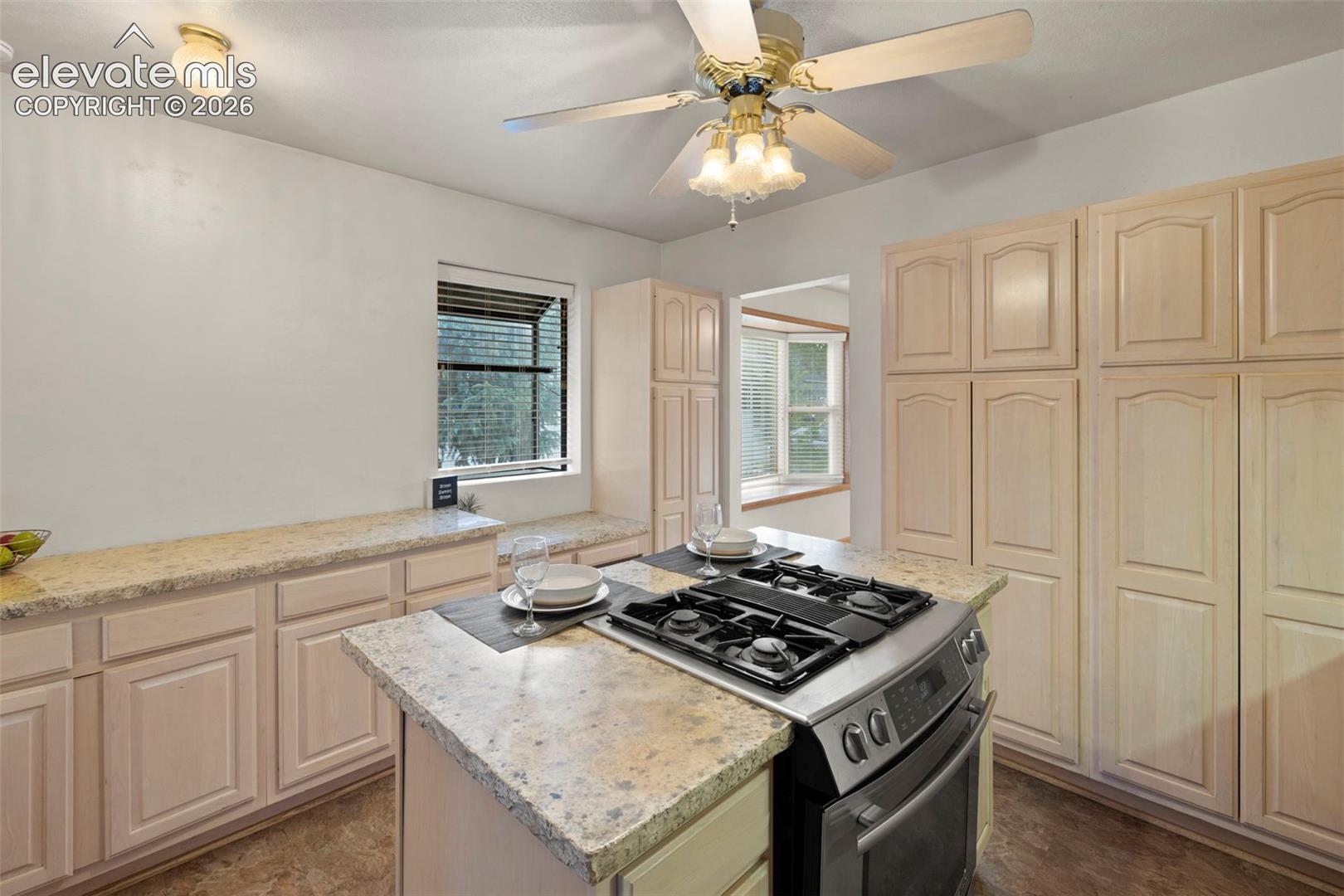 Kitchen featuring a center island with built-in gas range, extensive cabinetry, light-toned countertops, and a window seat