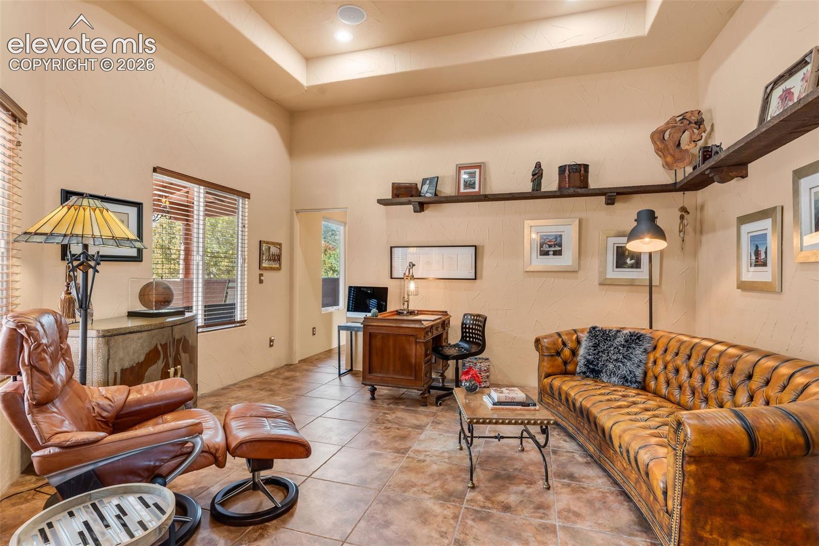 Tray ceiling with recessed lighting, tile flooring, and custom wall-mounted wood shelving