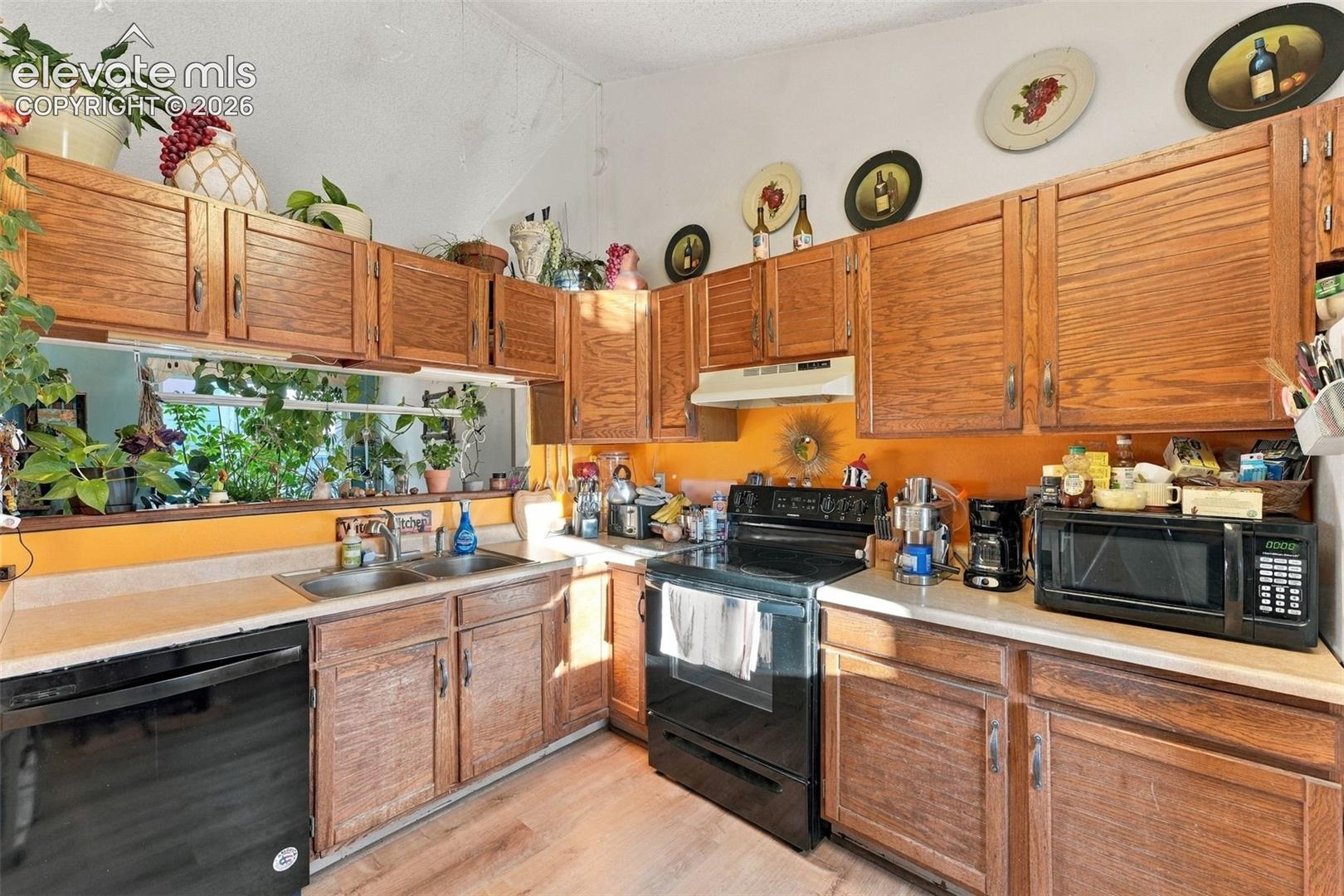 Kitchen featuring wood cabinetry, solid-surface countertops, dual-basin stainless steel sink, and wood-finish flooring