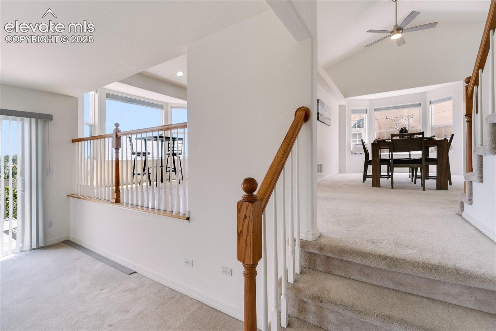 Staircase with wood newel posts and balusters, vaulted ceilings, and bay windows