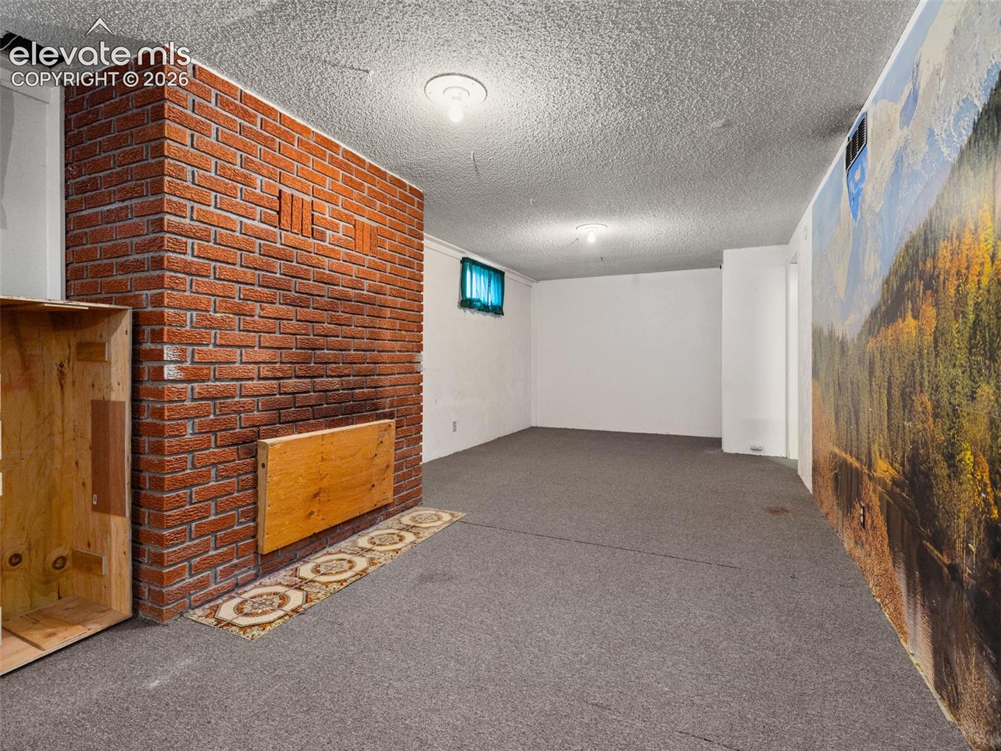 Brick accent wall with  textured ceiling, and  carpeting - family room