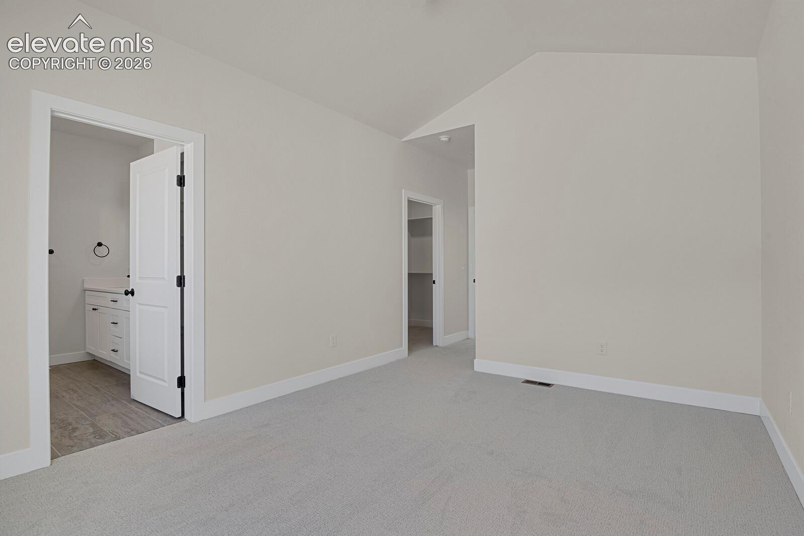 Vaulted ceilings and neutral carpeting featured throughout this room, complemented by interior doors and a built-in walk-in closet