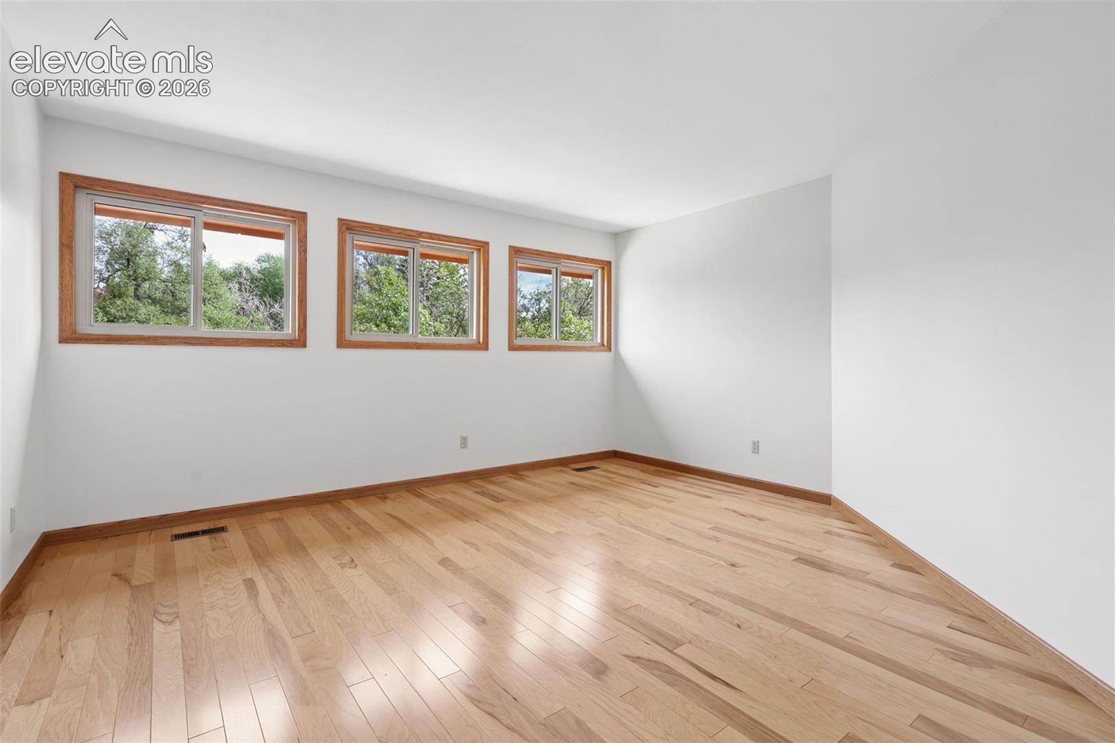 Spacious primary bedroom with attached 3/4 remodeled bath.  Bedroom features hardwood flooring.