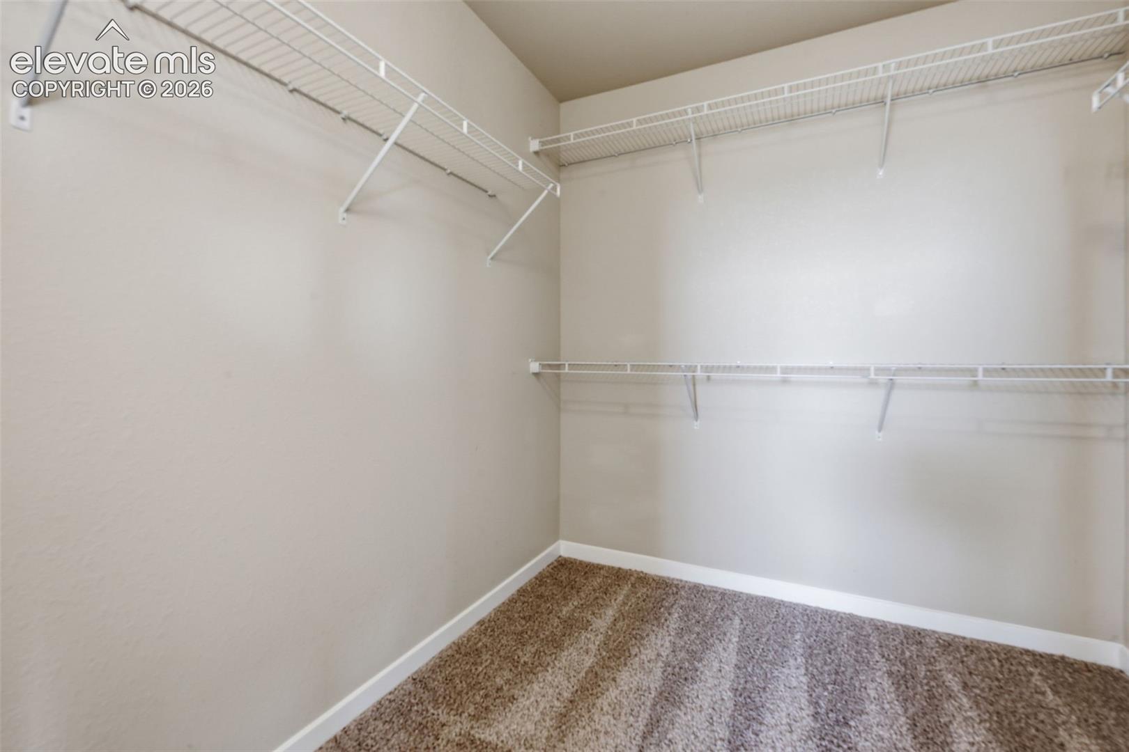 A generously sized walk-in closet with wraparound shelving provides plenty of organized storage.