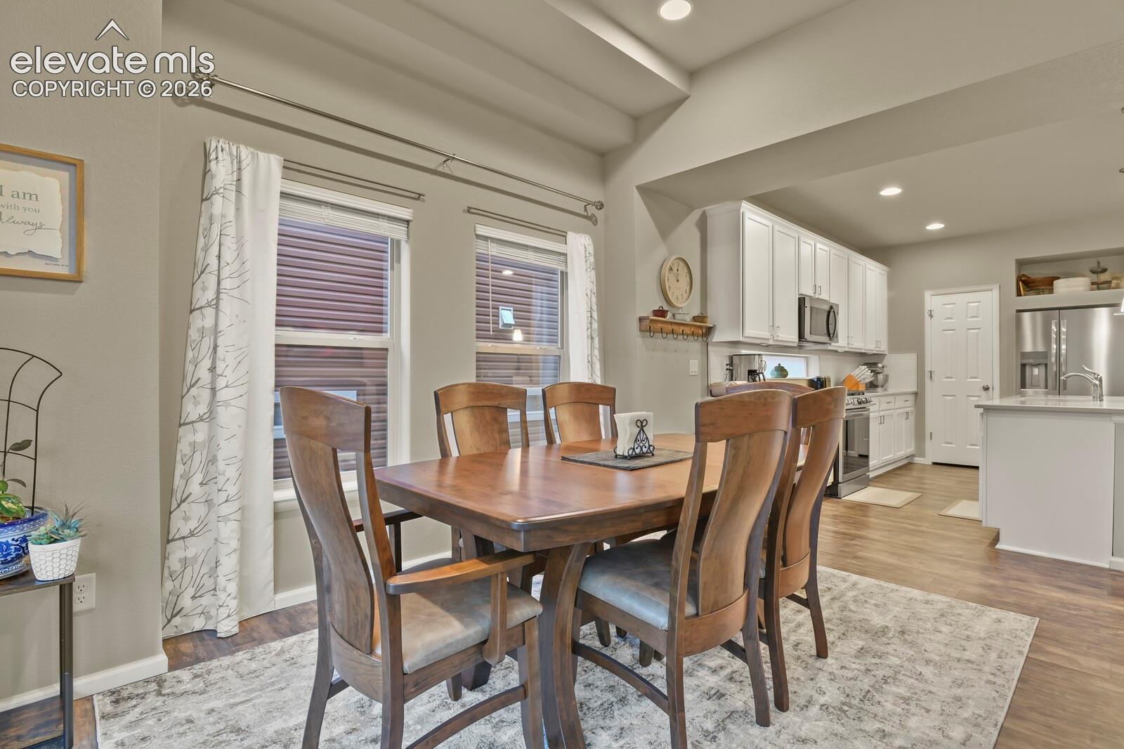 Open-concept area featuring white shaker-style cabinetry, Upgraded stainless steel appliances, recessed lighting, wood-finish luxury tile flooring, and tray ceiling detail