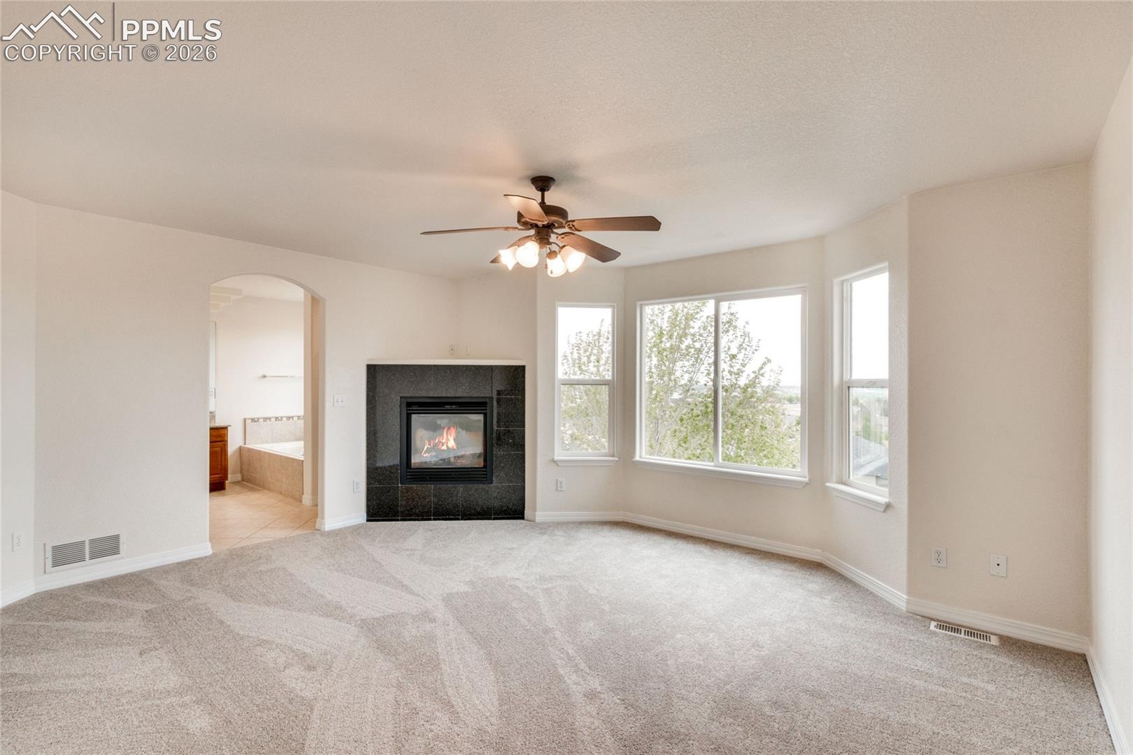 Primary bedroom with corner fireplace featuring a dark tile surround, and bay window with views of downtown.
