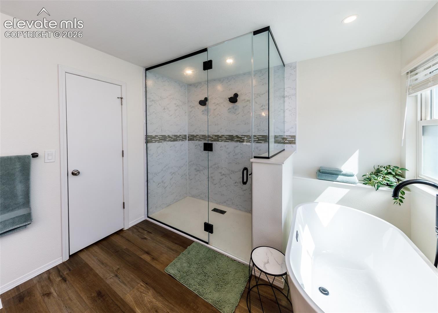 Glass-enclosed shower with tiled walls and dark bronze fixtures