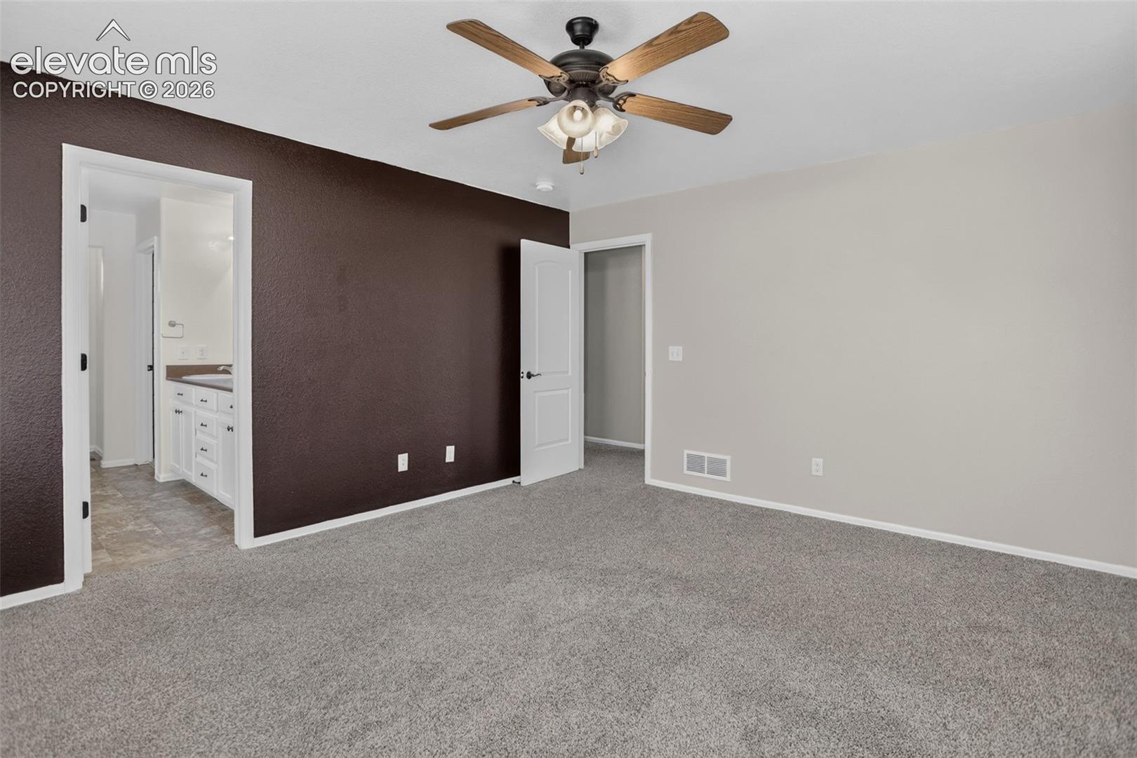 Neutral wall finishes, textured accent wall, ceiling fan with light fixture, gray carpet, and white trim