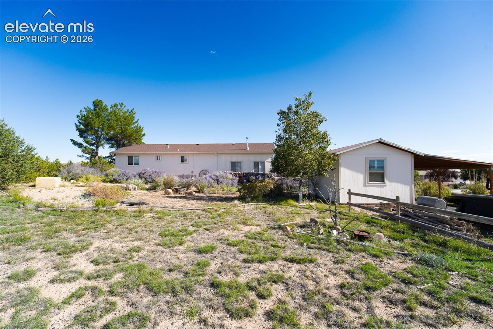 Exterior grounds featuring a multi-structure property, attached covered patio, post-and-rail wood fencing, and xeriscaped landscaping