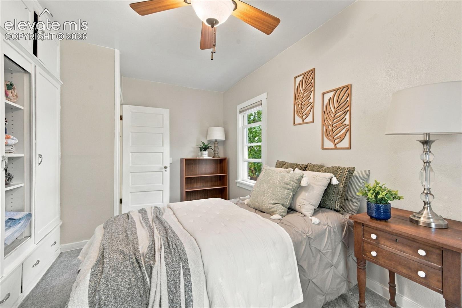 Bedroom featuring white built-in cabinetry, ceiling fan, and multi-panel interior door
