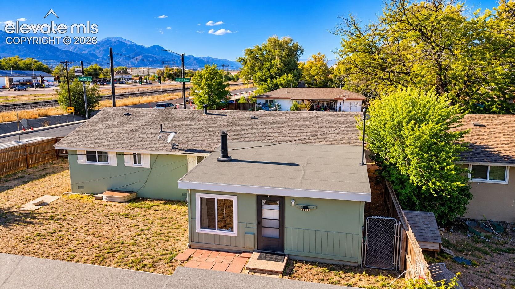 Elevated view showcasing the home's exterior, roofline, and surrounding neighborhood, with the beautiful Front Range mountains providing a scenic backdrop.