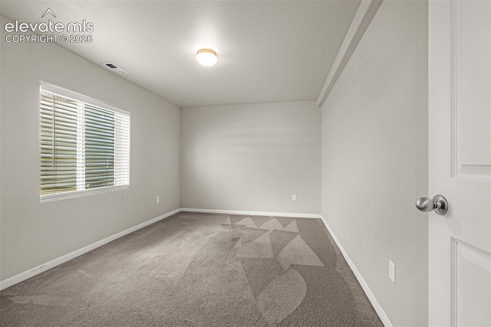 Neutral tone walls, ceiling-mounted light fixture, and carpeted flooring