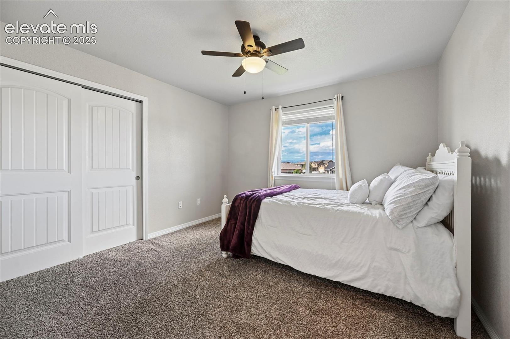 Neutral wall paint, carpet flooring, a ceiling fan with integrated lighting, and a window with blinds