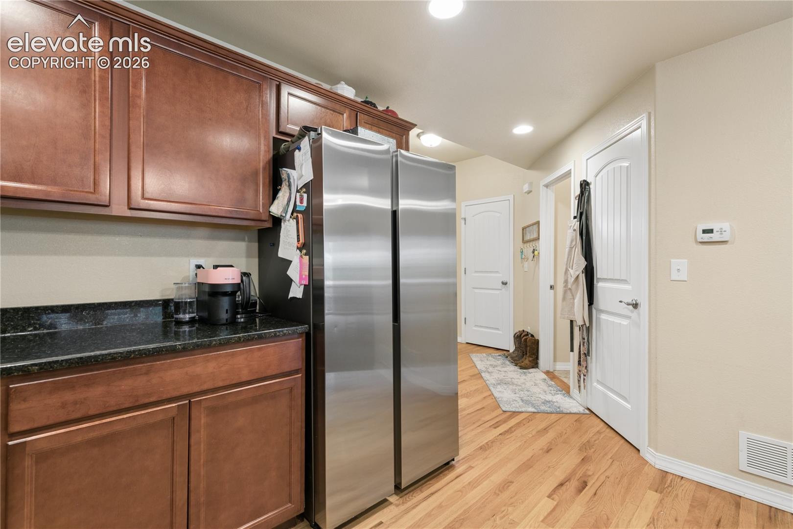 Kitchen area featuring wood-finish cabinetry, dark countertop, and a stainless steel refrigerator