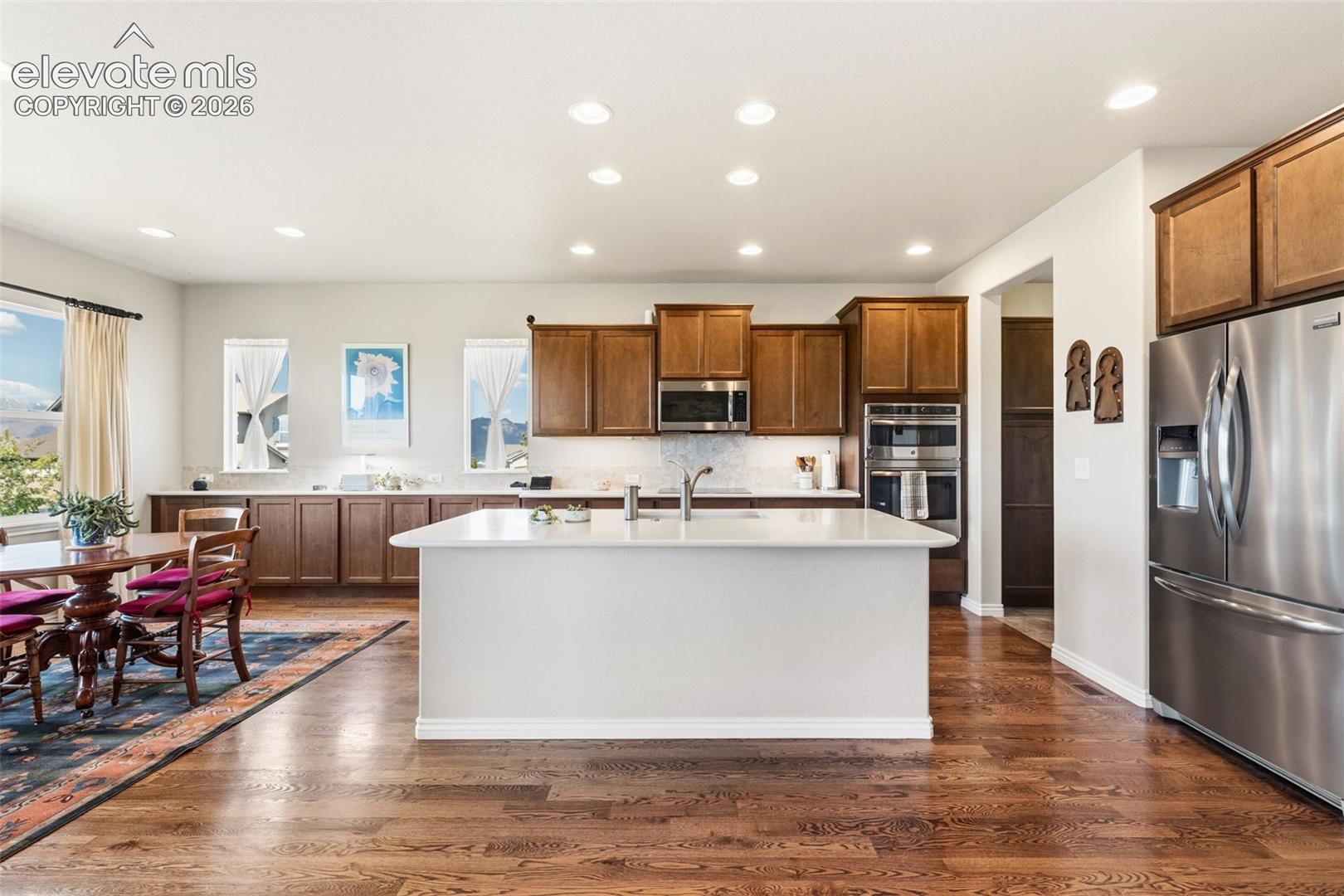 Open floor plan of kitchen and eat-in area featuring mountain views, hardwood flooring, stainless appliances, quartz counters