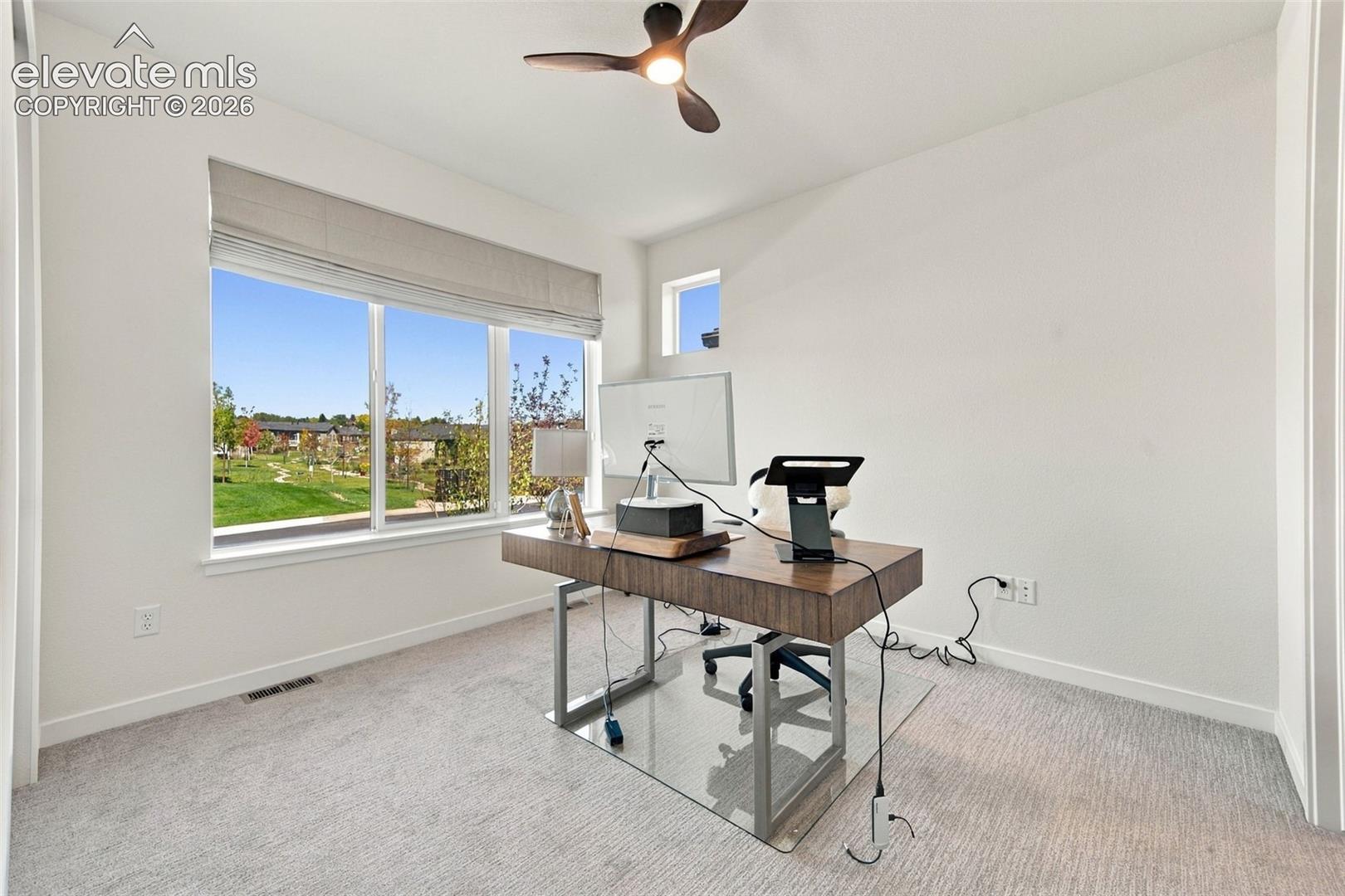 Neutral interior space featuring carpeted flooring, a ceiling-mounted fan with integrated lighting, a large picture window, and a high-set accent window