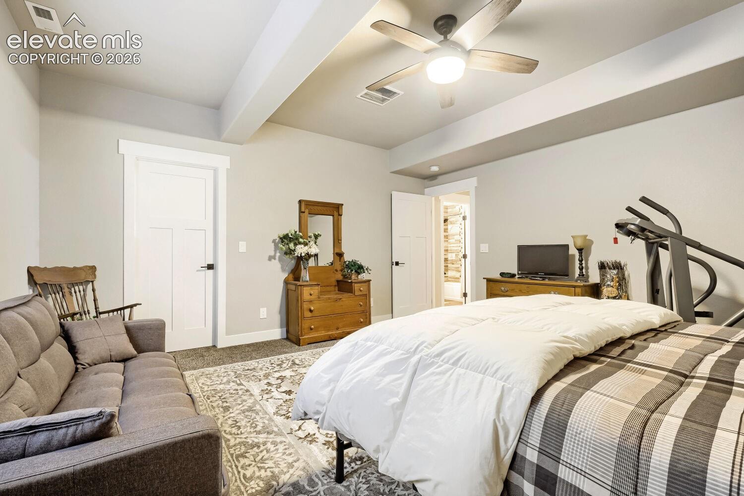 Recessed ceiling beams, ceiling fan with integrated lighting, and a paneled interior door with matte black hardware