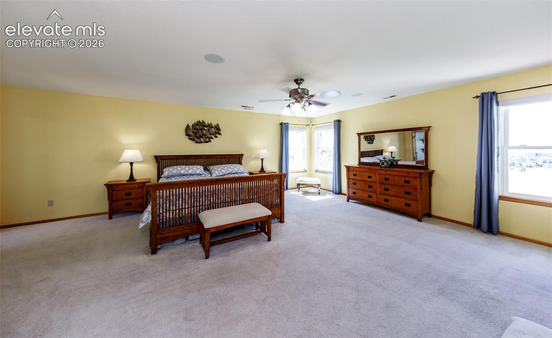 Expansive carpeted room with multiple windows, a ceiling fan, and recessed lighting